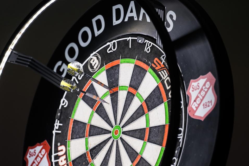 Zwei Pfeile stecken in einem Dartboard, umringt von einem beleuchteten Rahmen mit der Aufschrift „GOOD DARTS“.