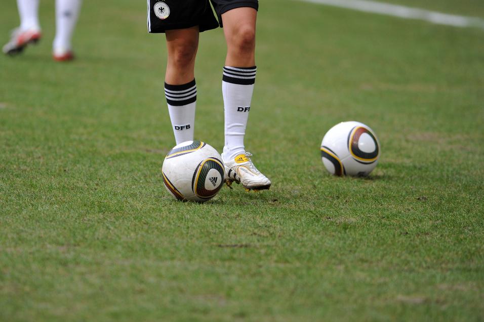 Nahaufnahme eines Fußballspielers mit einem Ball auf dem Rasen, im Hintergrund ein weiterer Ball.